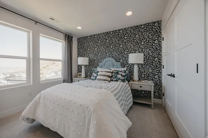 Bedroom featuring two large windows with white trim, patterned accent wall, recessed lighting, and light gray carpet