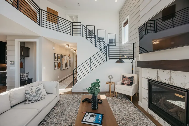 Two-story living area featuring a prominent staircase with black horizontal bar railings