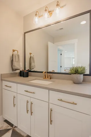 Bathroom vanity featuring a single undermount sink, brass-finish faucet, and substantial countertop space