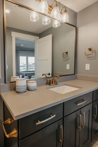 Bathroom vanity featuring dark wood cabinetry, a light-toned countertop with an integrated sink, and a gold-finish faucet