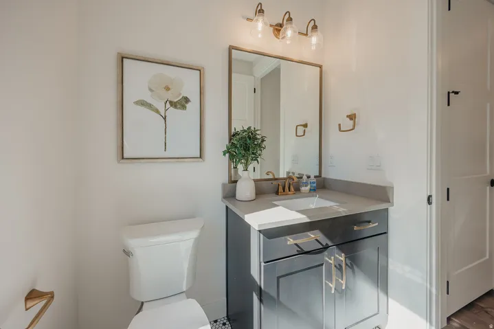 Vanity featuring dark cabinetry with gold hardware, a rectangular undermount sink, and a light-toned countertop