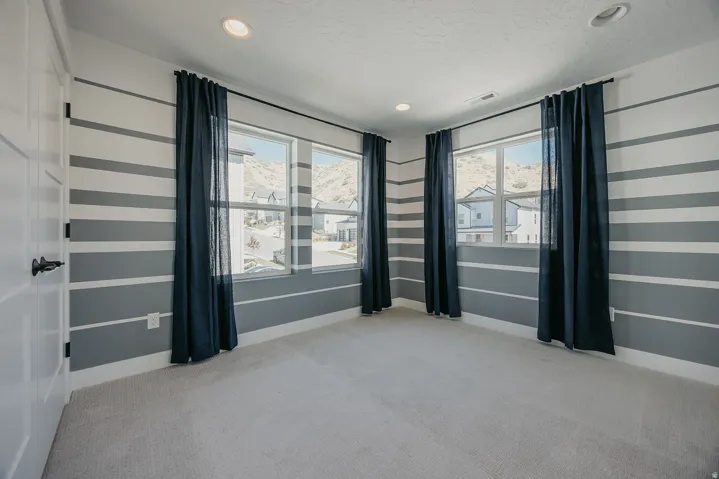 Room featuring horizontal striped accent walls, recessed lighting, and light-toned carpeting