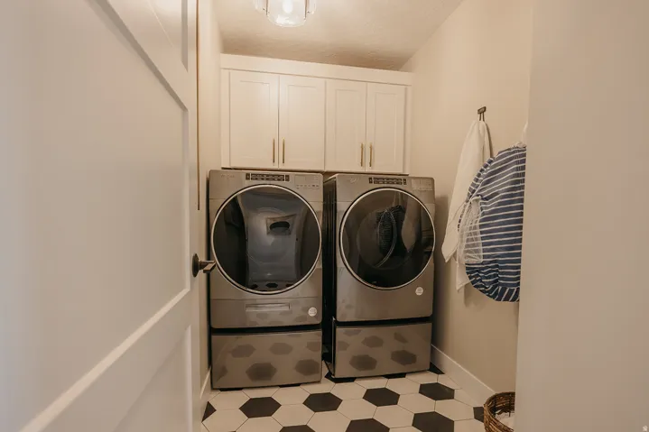 Laundry area featuring hexagonal tile flooring, upper cabinetry with brushed nickel hardware, and a ceiling-mounted light fixture