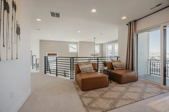 Upper-level landing featuring a sliding glass door to a private balcony, recessed lighting, and a modern horizontal railing system