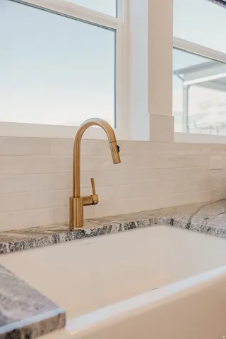 Farmhouse sink with a gold-tone gooseneck faucet, set against a white subway tile backsplash and variegated stone countertops