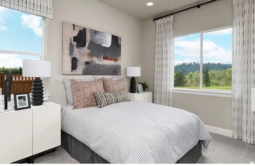Bright room featuring two large windows, one with a roman shade and the other with sheer curtains, recessed lighting, and soft gray carpet