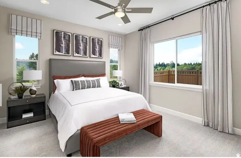 Carpeted bedroom featuring a ceiling fan, dual windows with Roman shades, and a large window with floor-length drapes