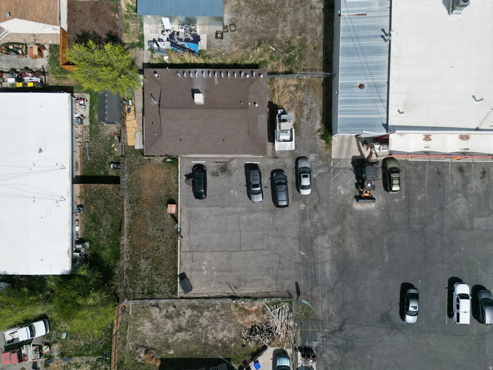 Aerial perspective showcasing a parcel with a brown-roofed building and a paved parking area