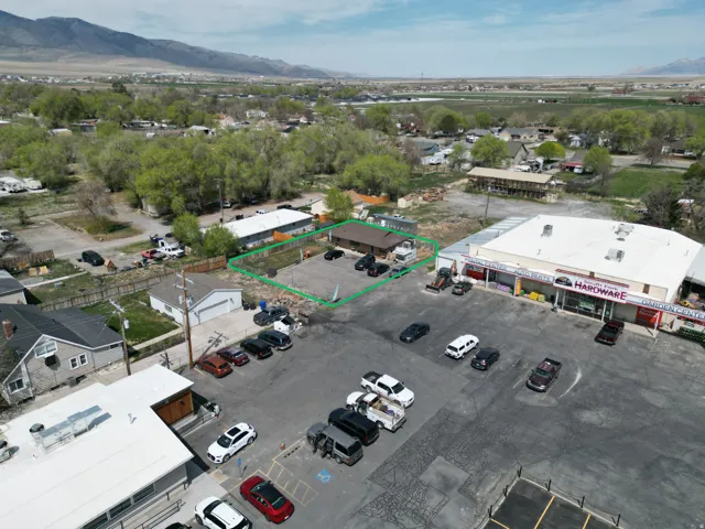 Commercial property featuring an asphalt parking area, adjacent retail building, and a fenced perimeter