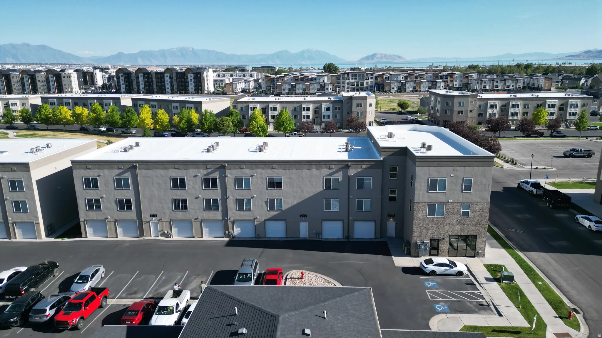 Multi-story building featuring a stucco and stone facade, ground-level garages, upper-story windows, and a flat roof