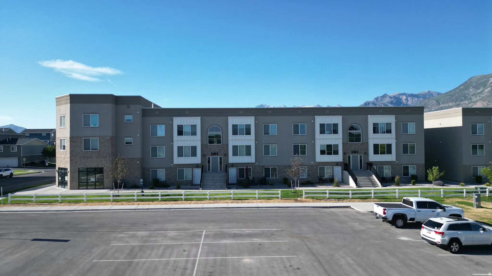 Modern multi-story building featuring a gray and white facade with stone accents