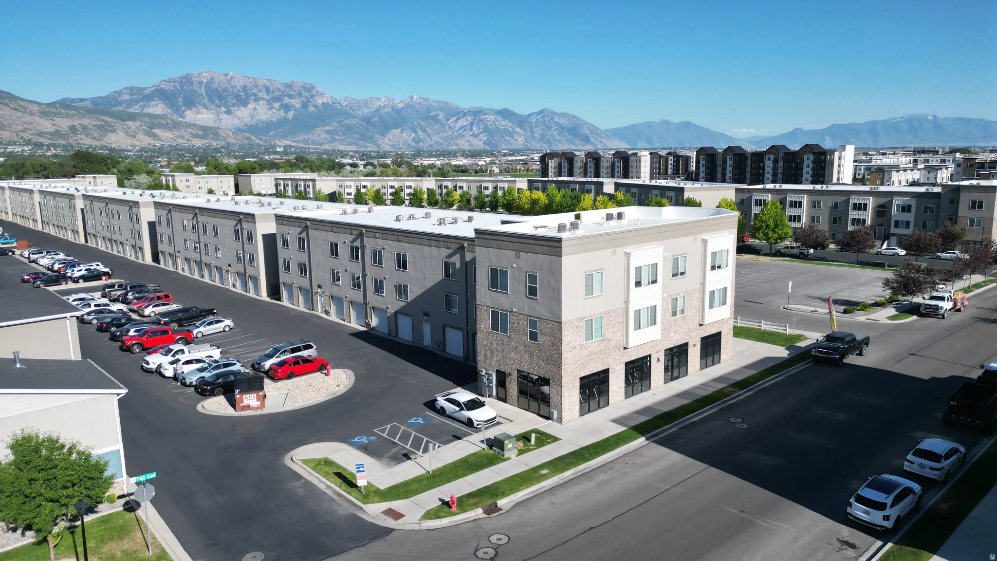 Contemporary mixed-use building featuring ground-floor commercial space, upper-level residential units, and a mountain backdrop
