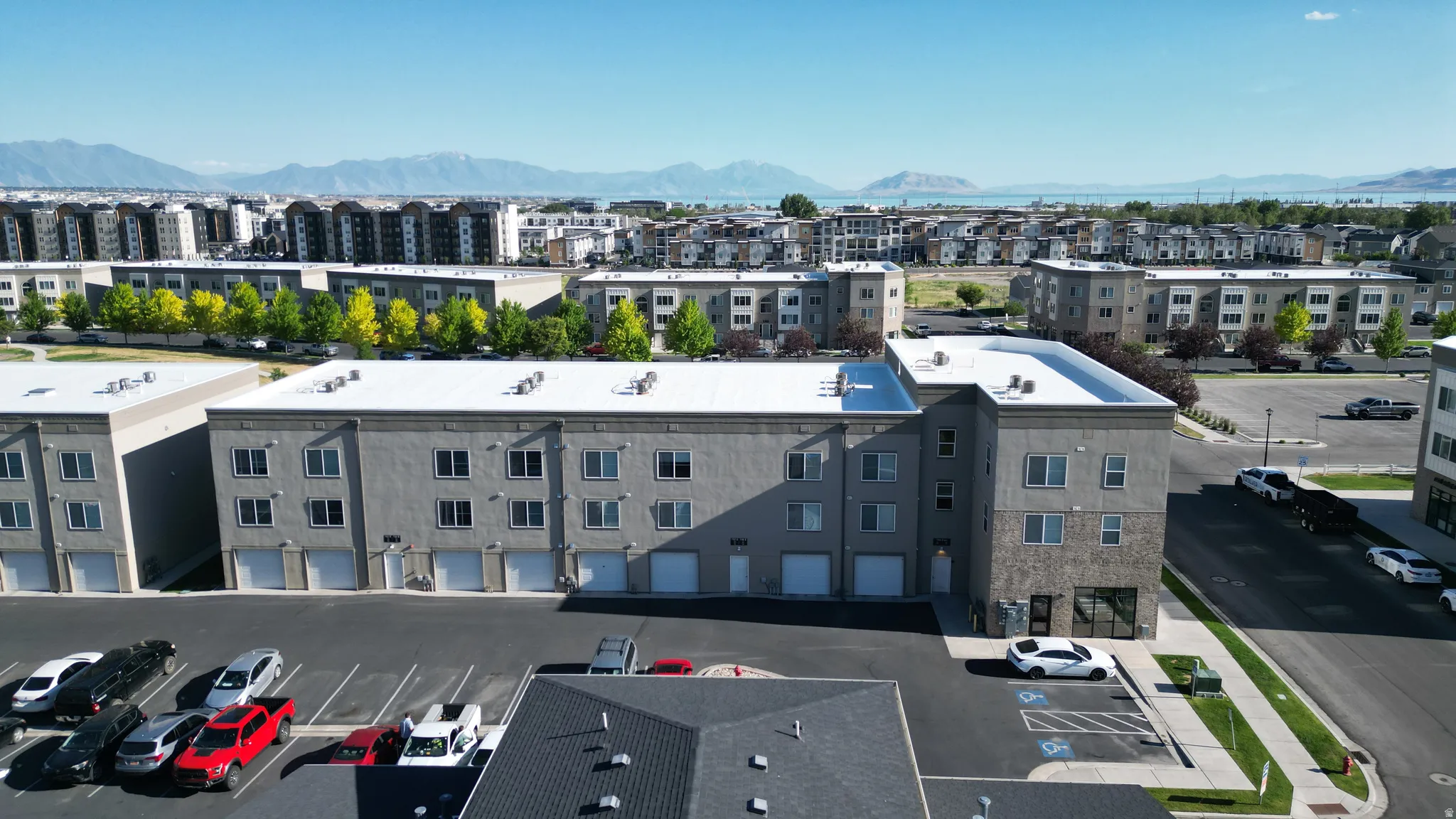 Multi-story commercial building featuring stucco and stone veneer exterior finishes, multiple garage doors, a flat roof, and a dedicated parking area