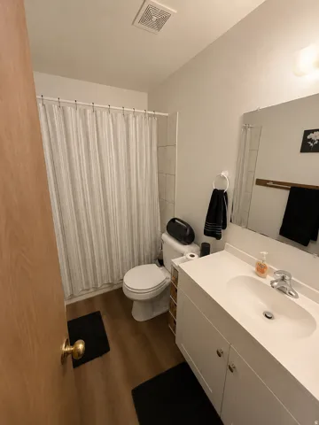 Unit B: Bathroom featuring a single vanity with an integrated sink, white cabinetry, and a chrome faucet