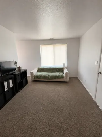 Unit B: Carpeted interior space featuring neutral wall tones and a window with blinds