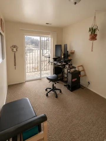 Unit C: Bright interior space featuring a sliding glass door with a security gate, neutral-toned wall paint, and textured carpet flooring