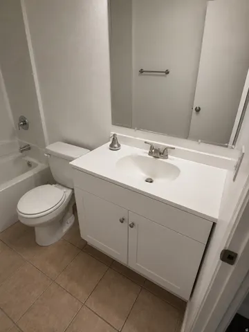 Unit A: Bathroom featuring a white vanity with an integrated sink, brushed nickel faucet, and a large wall mirror
