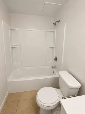 Unit A: Bathroom featuring a white bathtub and shower surround with integrated shelving