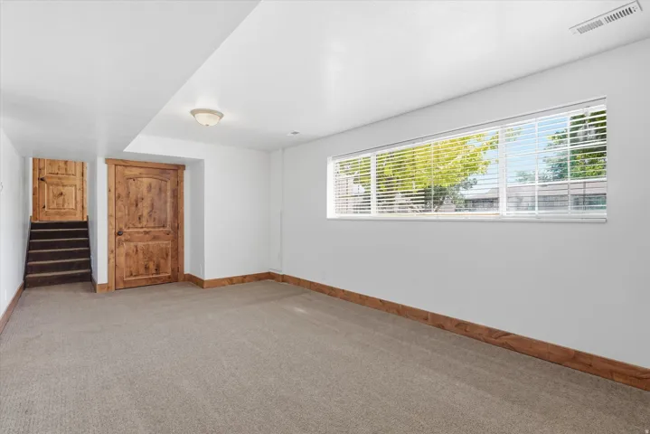 Carpeted room featuring a horizontal window with blinds, wood-finish doors, wood-finish trim, and recessed lighting