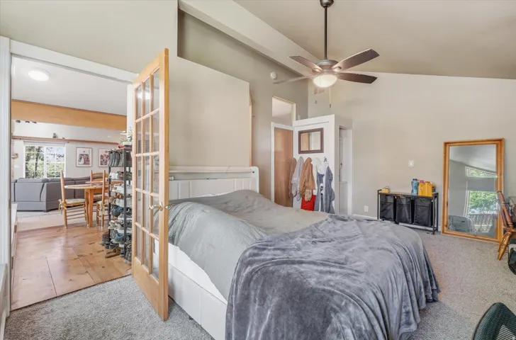 ADU Spacious Master bedroom with Stackable washer and dryer with vaulted ceiling, ceiling fan, and carpet flooring