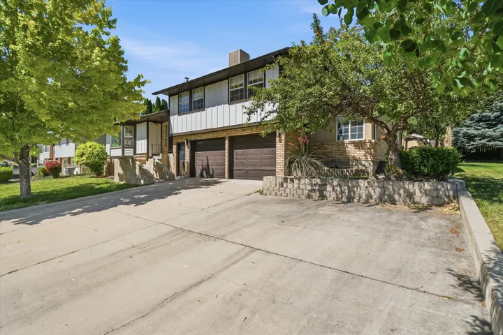 Two-story residence featuring a two-car garage with brown doors, a brick facade, white vertical siding, and a concrete driveway