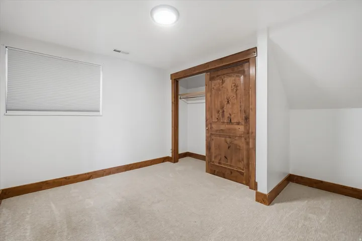 Carpeted room featuring a barn door entry to a closet, a window with blinds, recessed lighting, and wood trim accents
