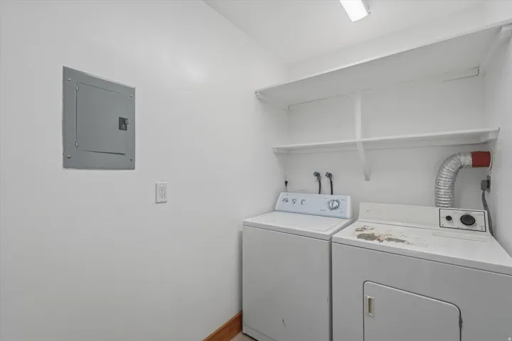 one of 3 Dedicated Laundry areas featuring overhead shelving, wall-mounted electrical panel, and wood-finish base trim