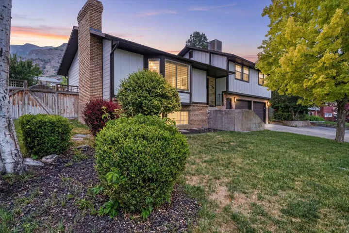 Split-level residence featuring a prominent brick chimney, multi-panel windows, and a two-car garage