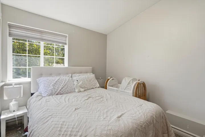 ADU Bedroom featuring a window with grid panes, a sloped ceiling, and neutral wall tones