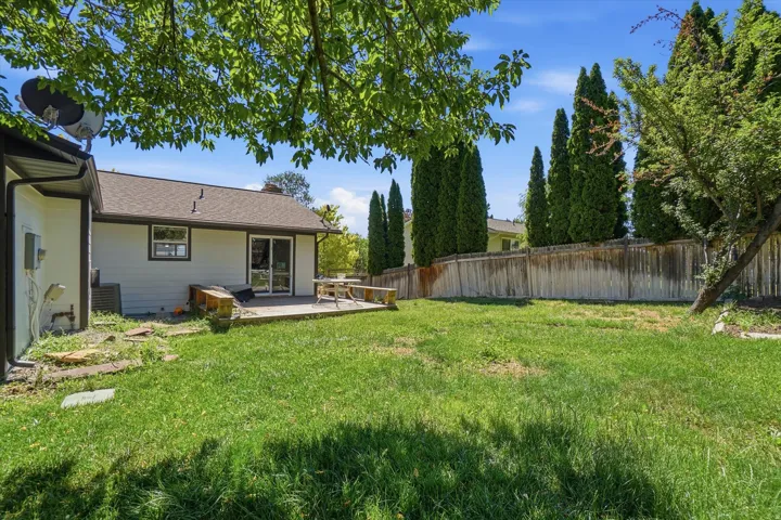 Expansive backyard featuring a manicured lawn, a wood deck, and perimeter fencing