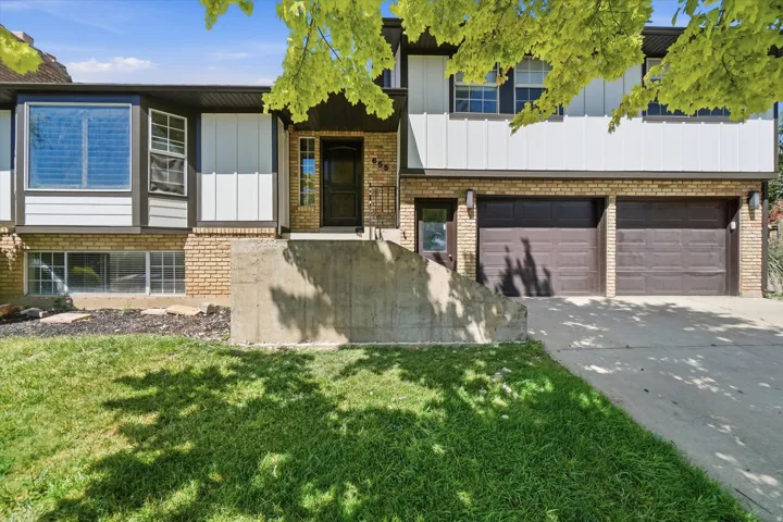 Split-level residence featuring a brick and siding exterior, bay window, and a two-car garage