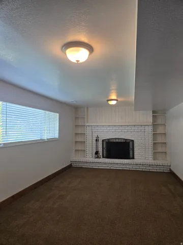Fireplace featuring a black metal screen, white painted brick, and built-in shelving