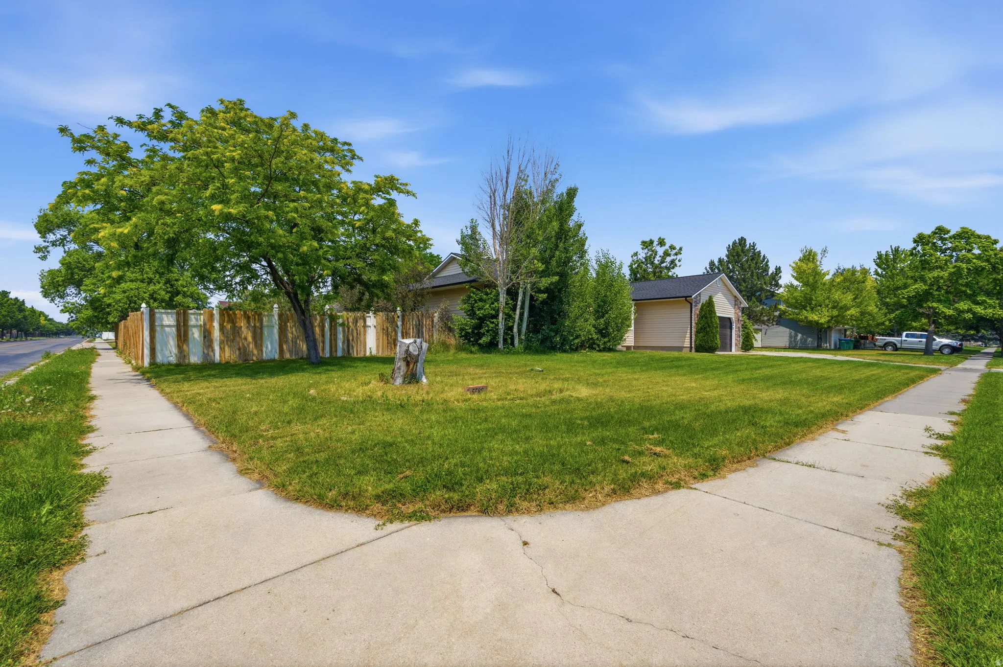 Expansive green lawn with established trees and a paved sidewalk