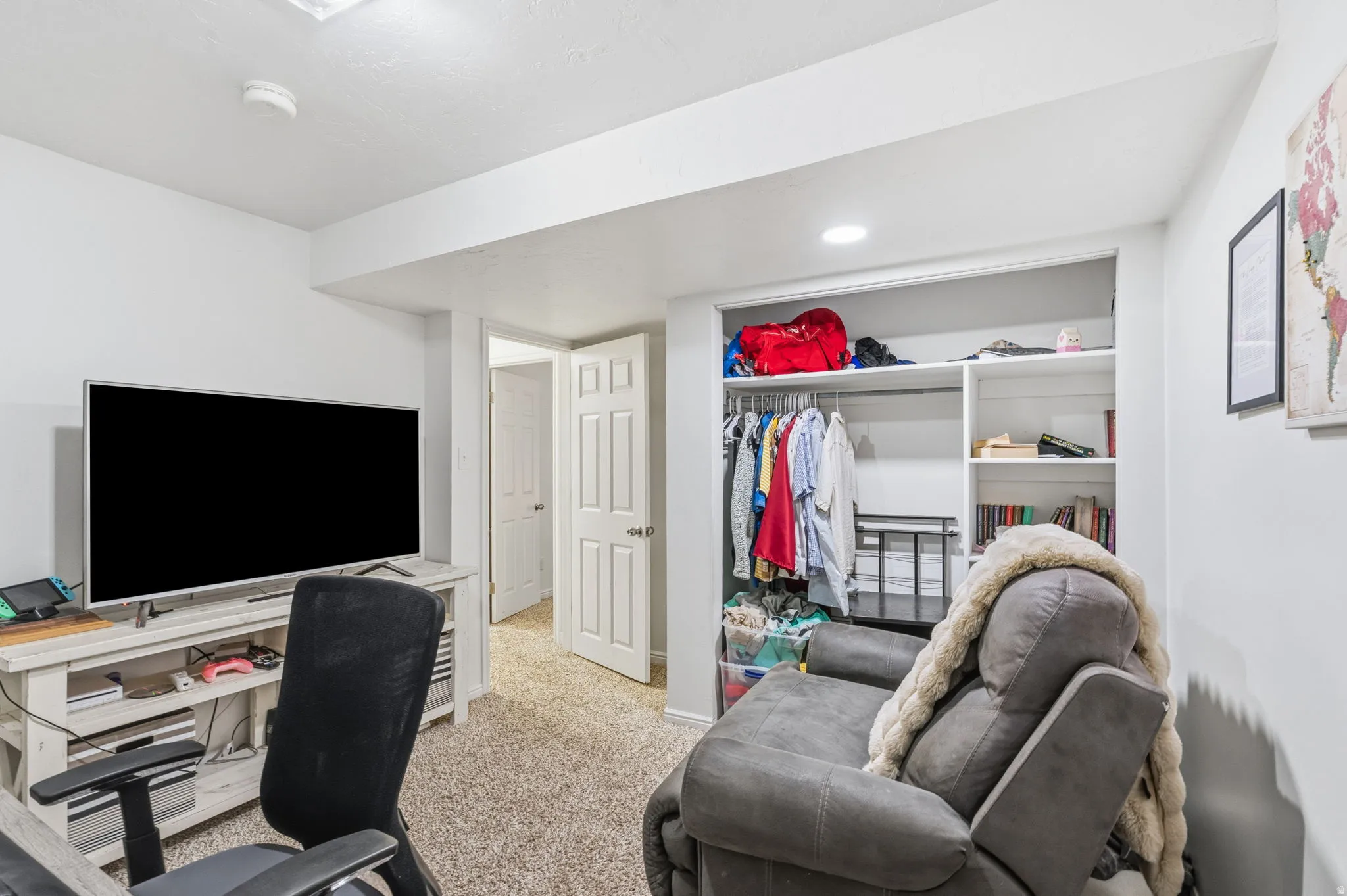 Recessed lighting illuminates this versatile space featuring light-colored carpeting and white walls