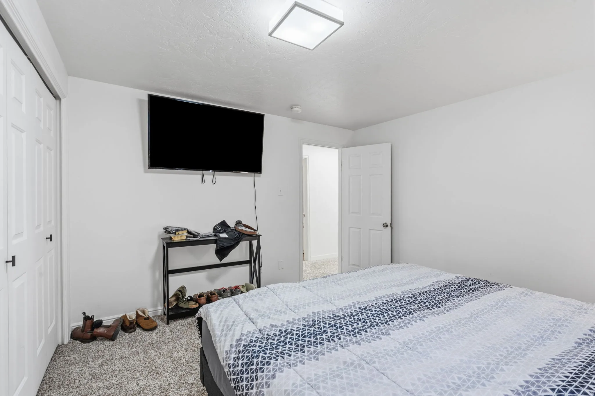 Carpeted room featuring white walls, a white paneled door, and a flush-mount ceiling light