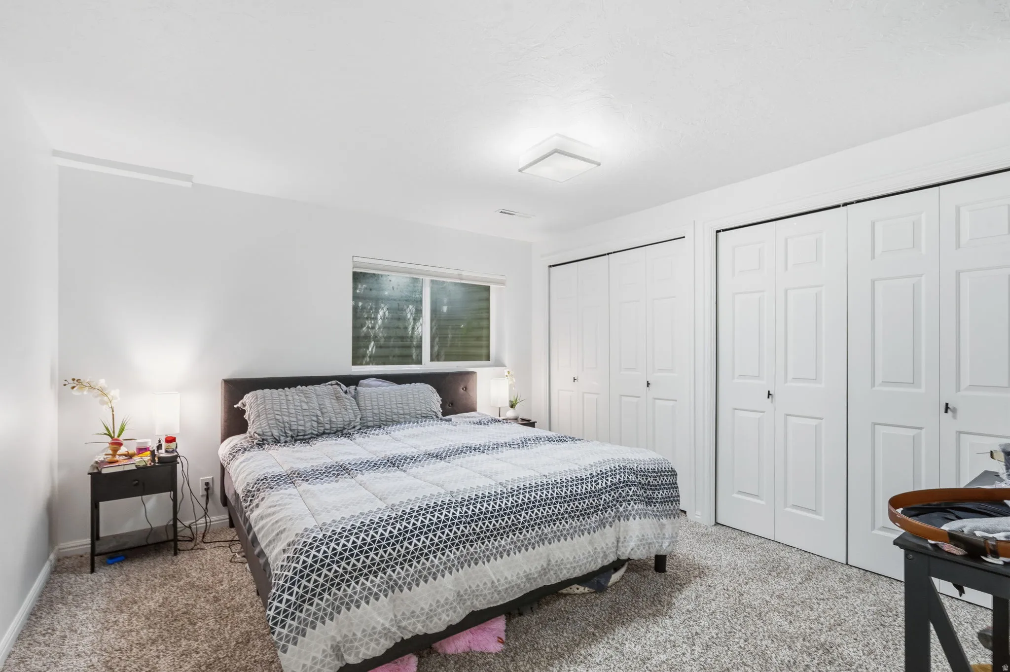 Carpeted bedroom with a window, recessed lighting, and multiple bi-fold closet doors
