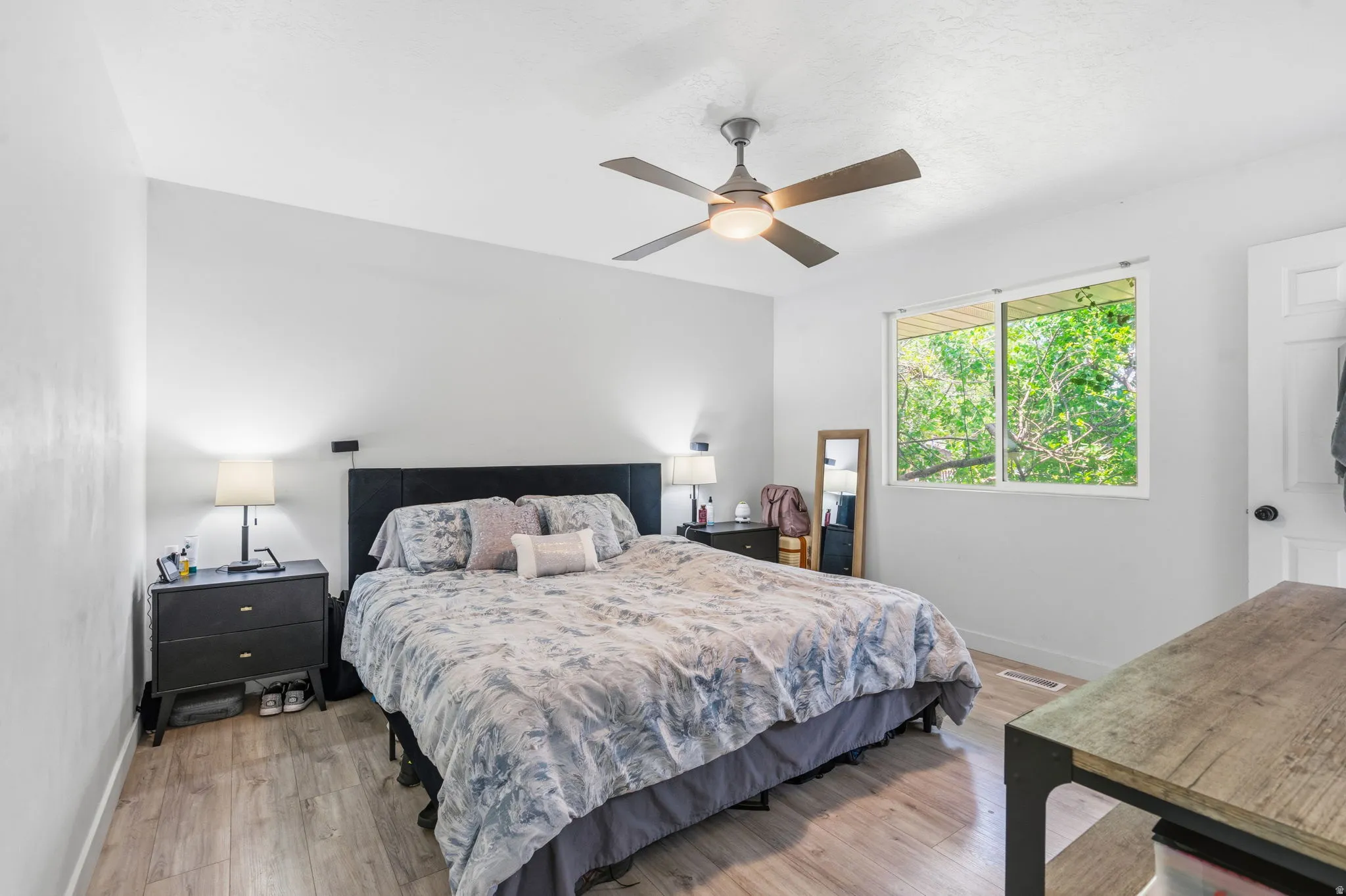 Bedroom featuring wood-finish flooring, a ceiling fan with integrated lighting, a rectangular window, and light-toned wall finishes