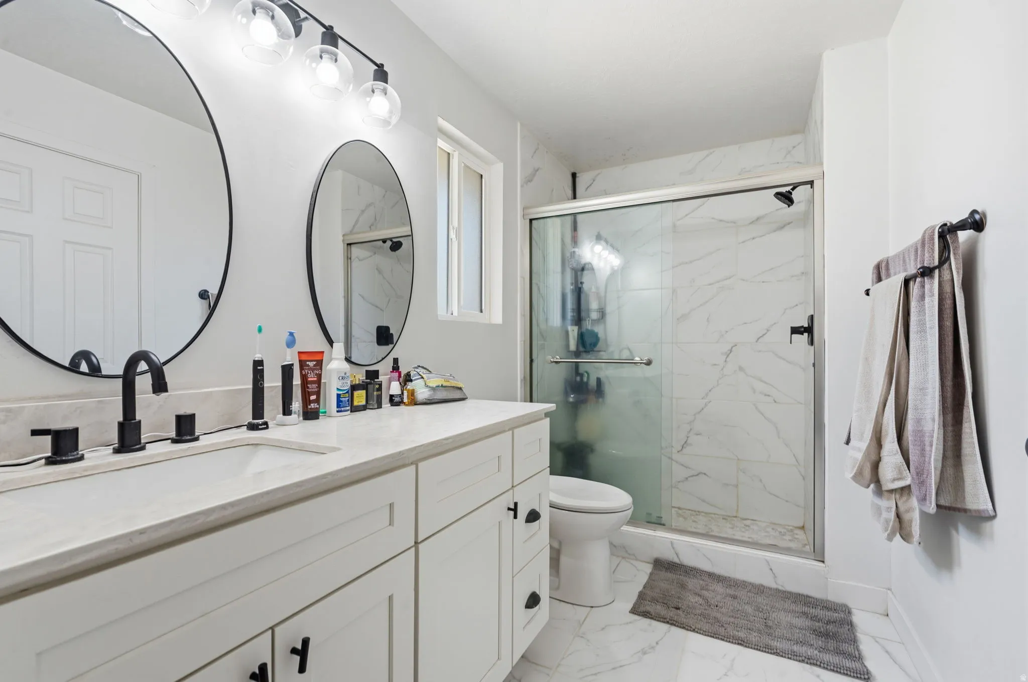 Double vanity with matte black fixtures and circular mirrors