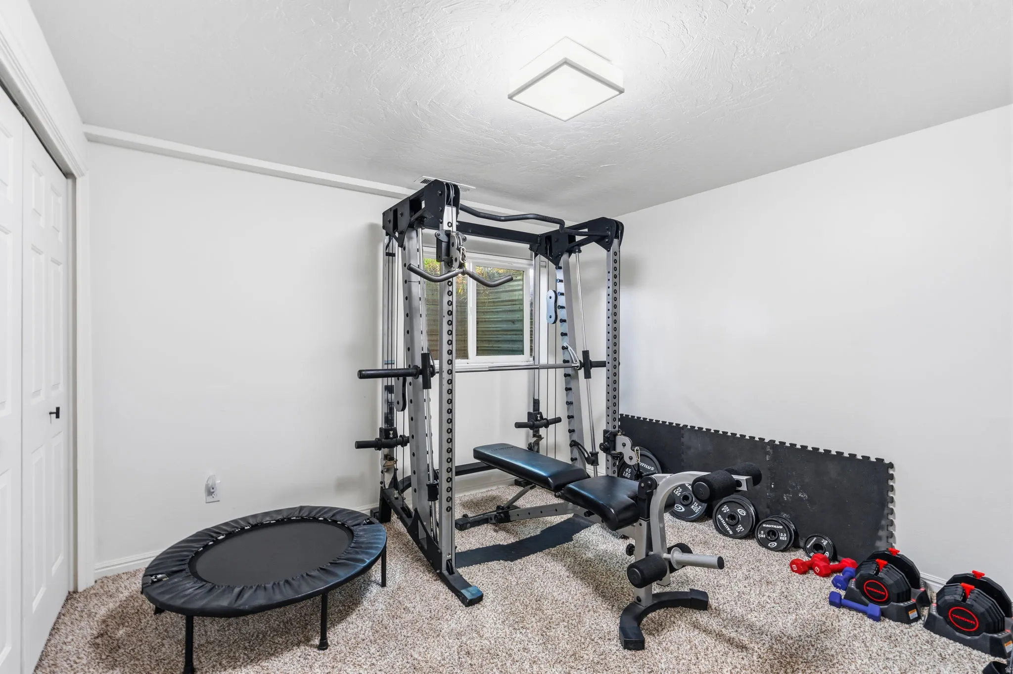 Carpeted room with a square flush-mount ceiling light and white walls