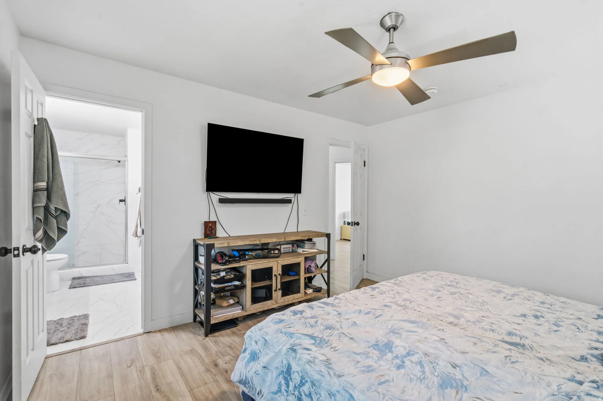 Bedroom featuring wood-finish flooring, a contemporary ceiling fan with integrated lighting, and white walls