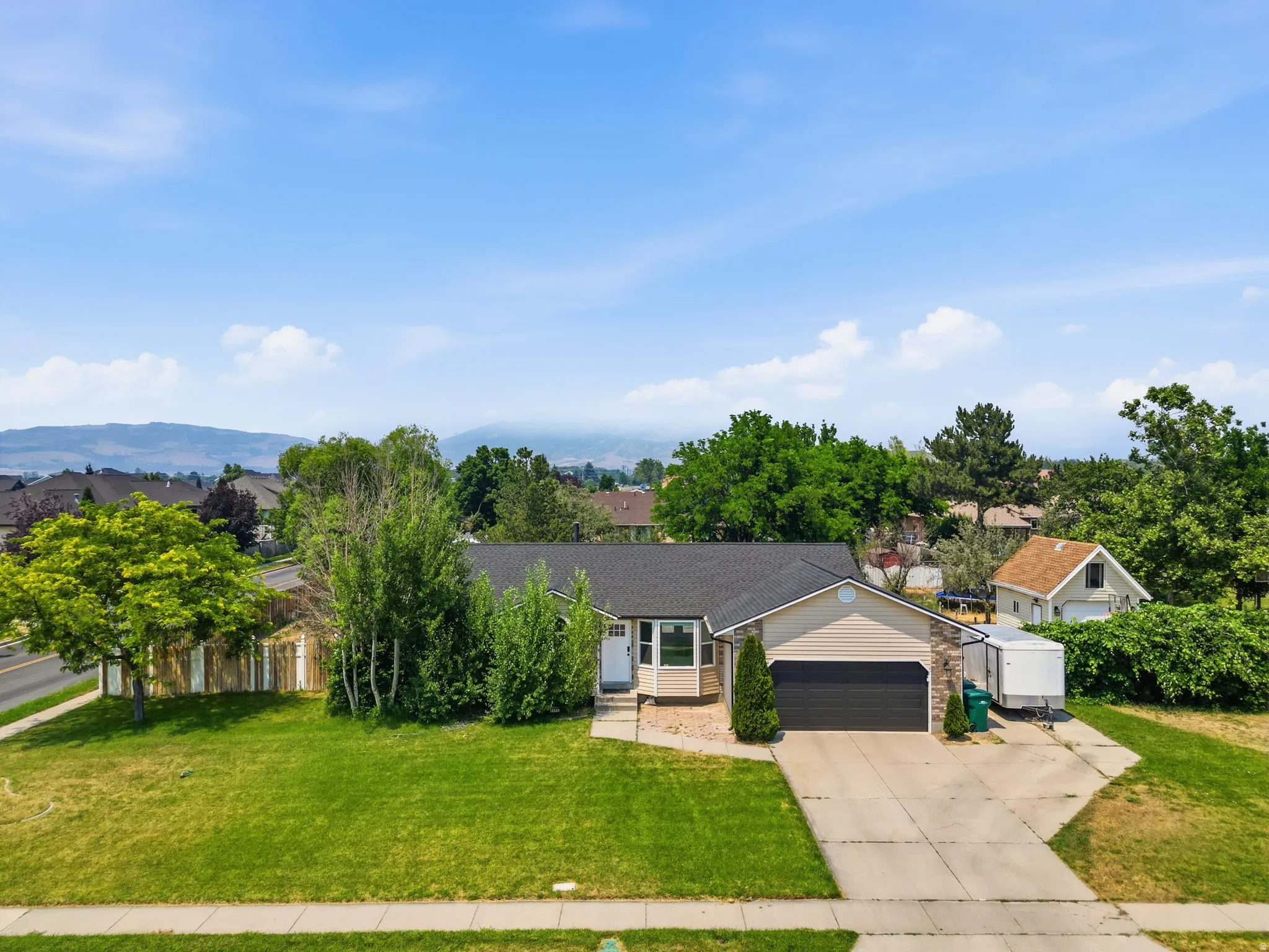 Ranch-style residence featuring a two-car garage, concrete driveway, and established front landscaping
