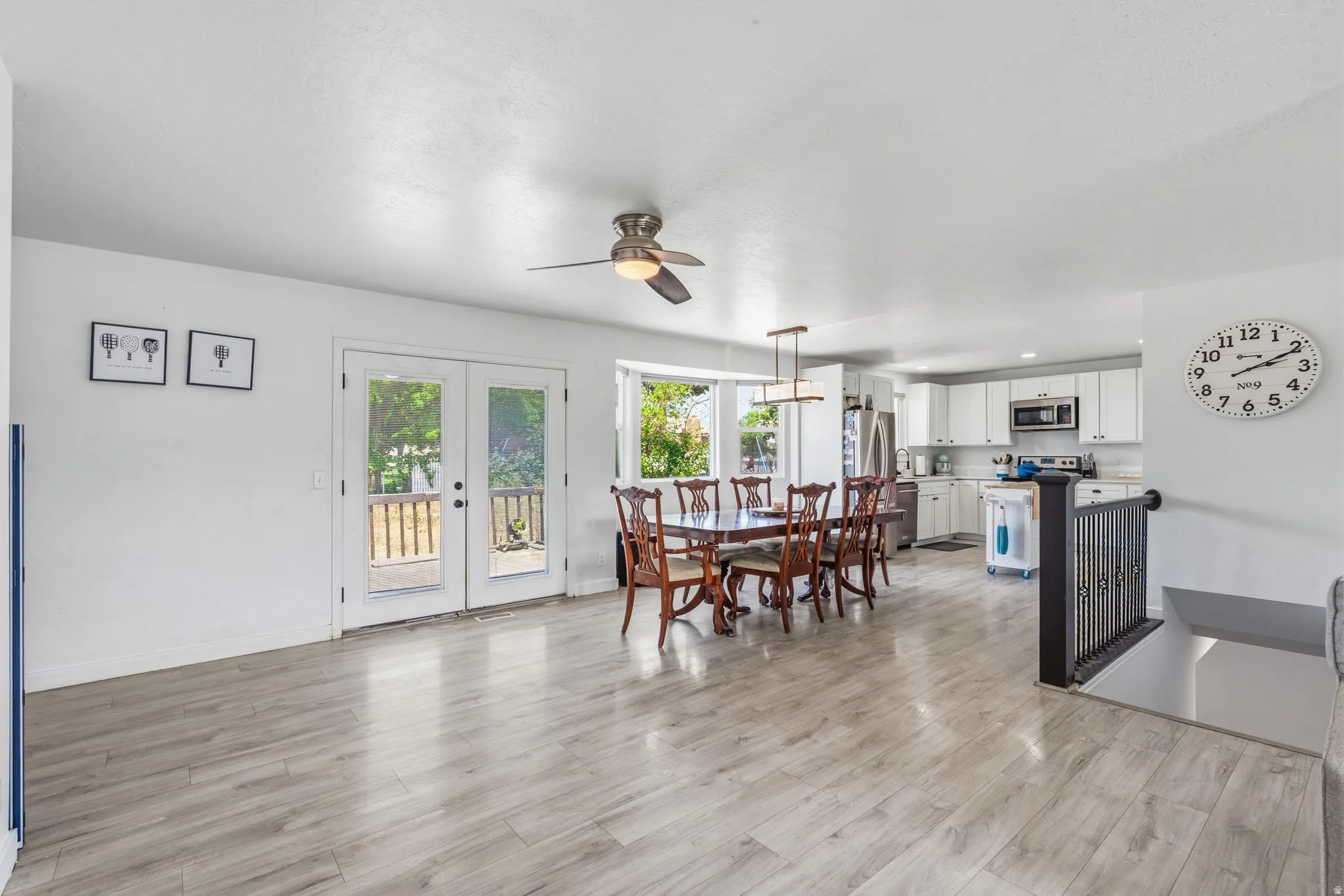 Open-concept living space featuring light wood-finish flooring, white walls, and a ceiling fan