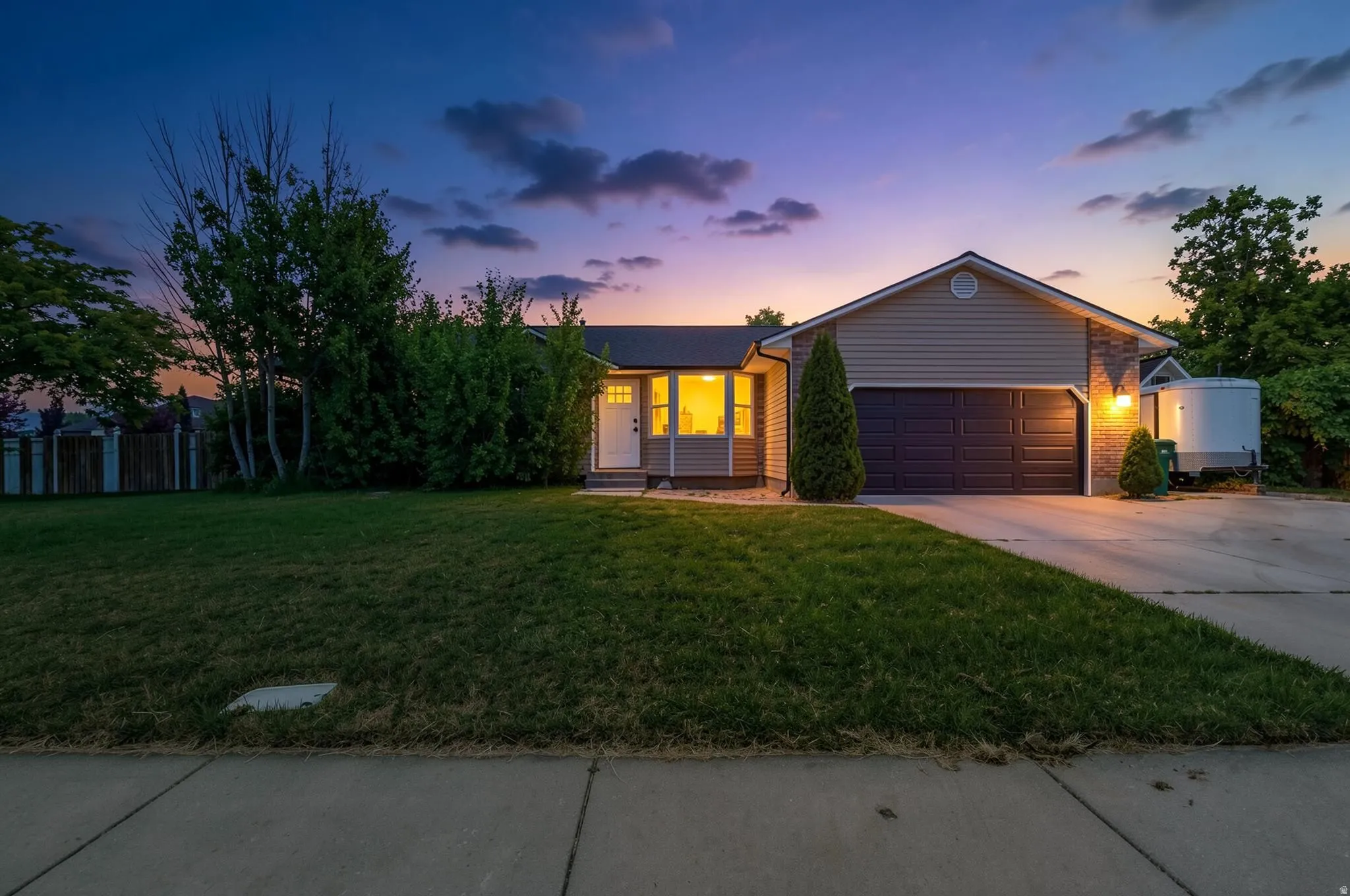Exterior featuring horizontal siding, brick veneer accents, an attached two-car garage, mature landscaping, and a concrete driveway