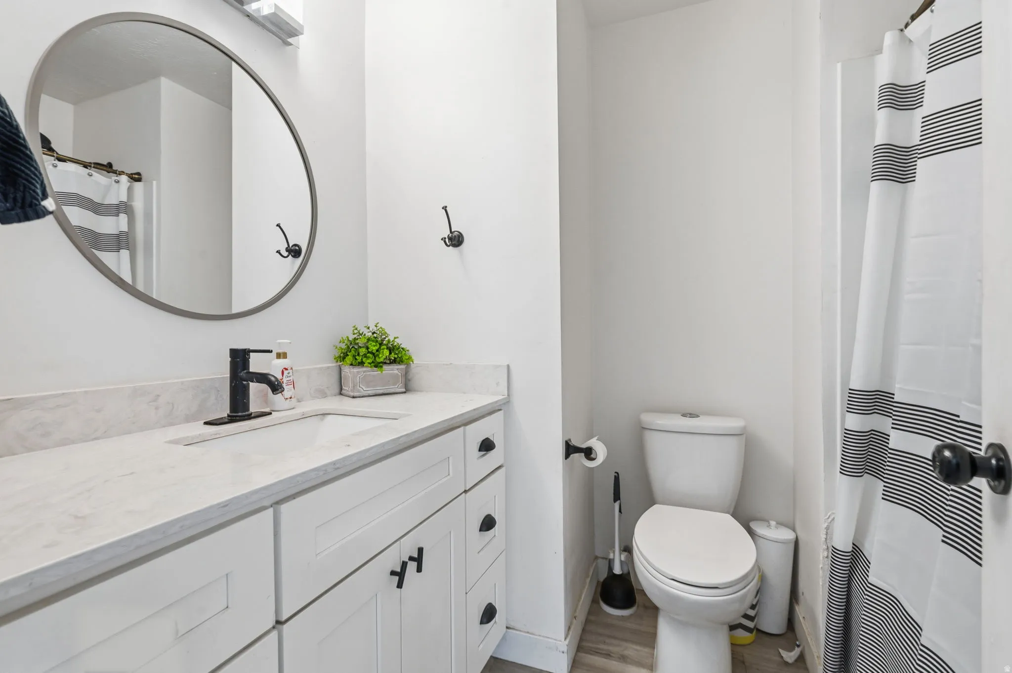 Bathroom featuring a white vanity with shaker-style cabinetry, a white countertop, and a rectangular undermount sink with a matte black faucet