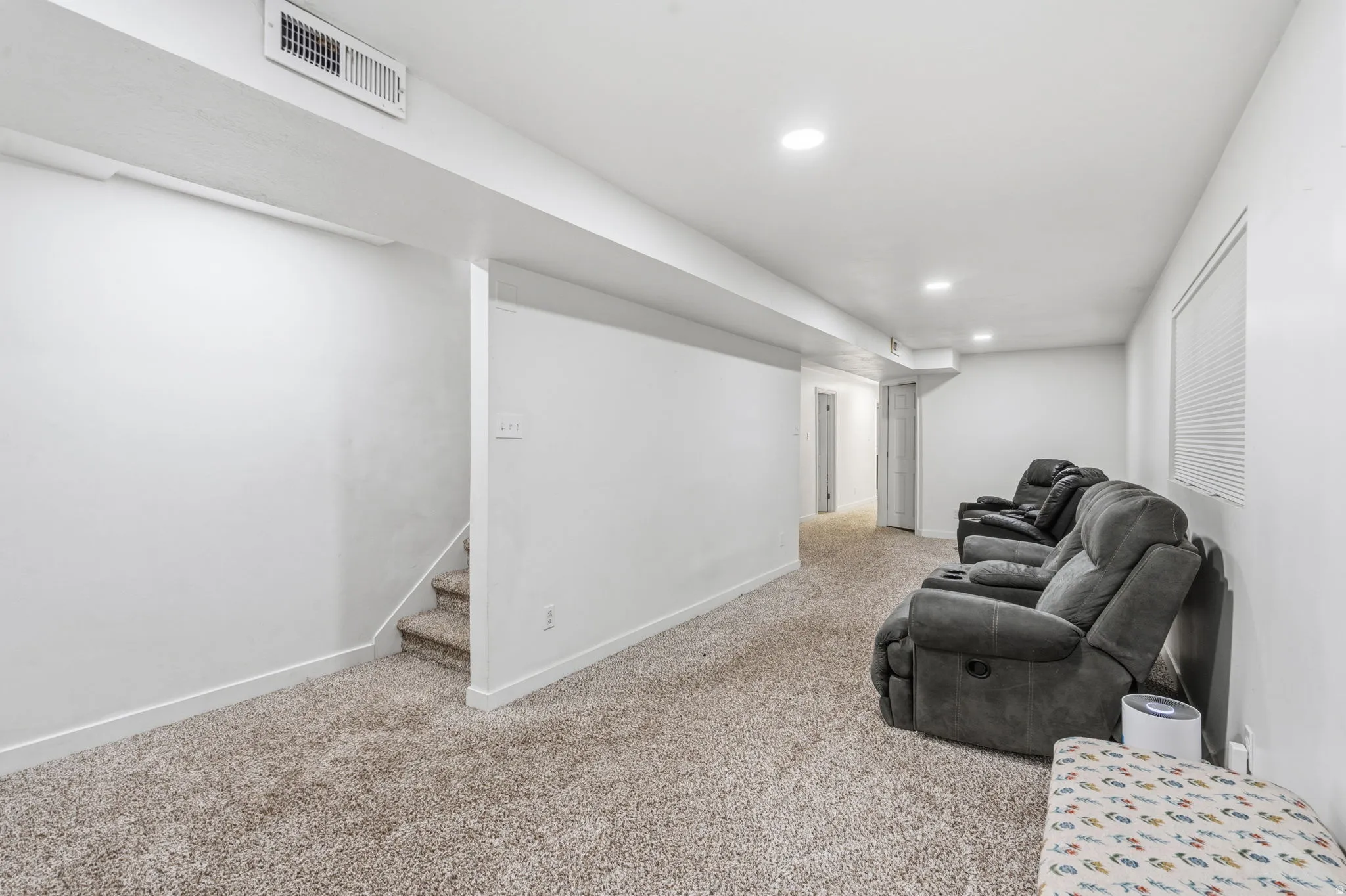 Carpeted lower level featuring recessed lighting, a window with horizontal blinds, and a built-in air vent