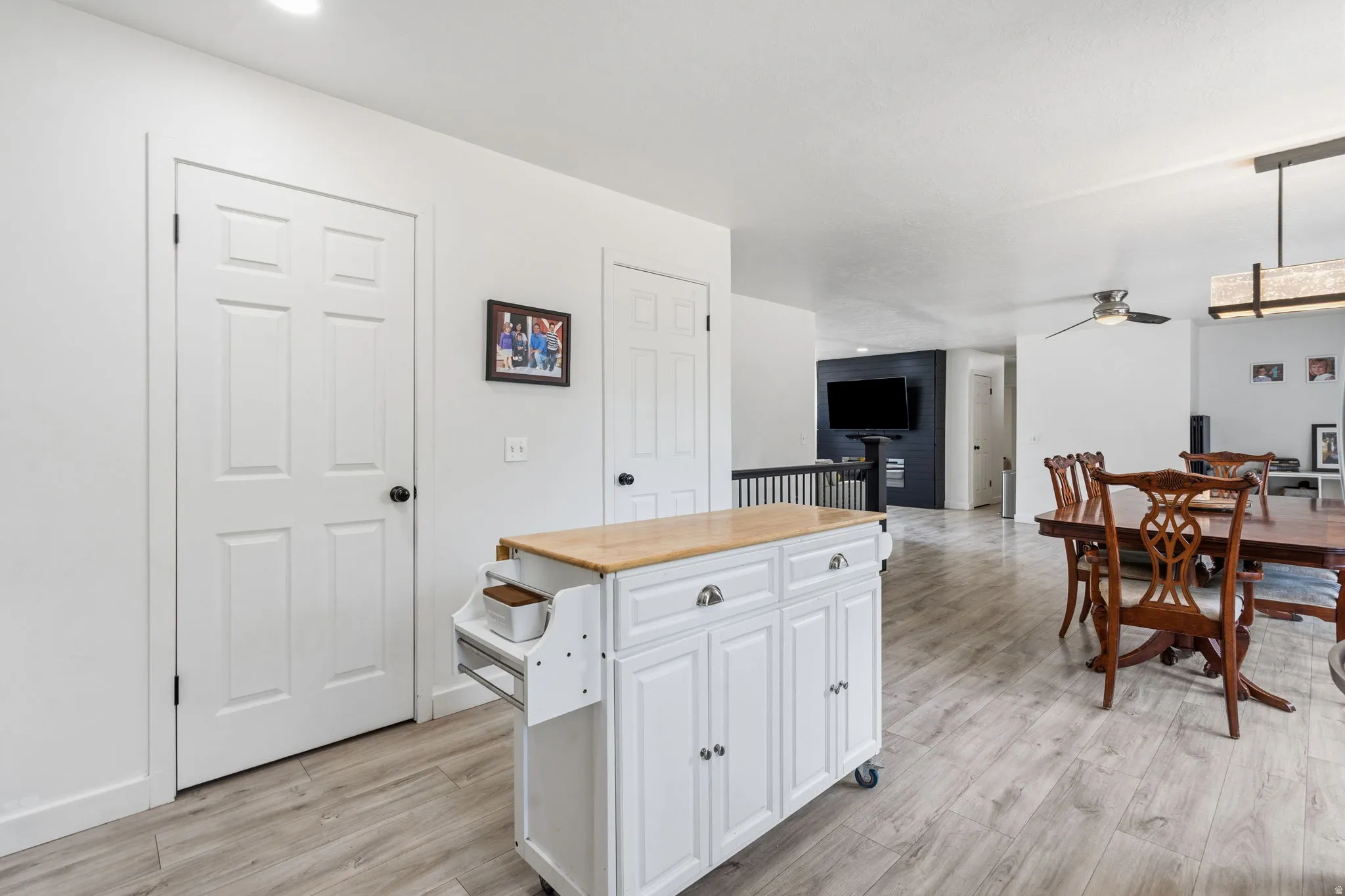 Open concept living area featuring light wood-finish flooring, white walls, and a modern ceiling fan