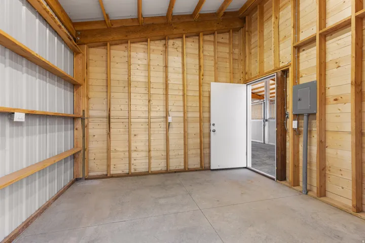 Utility room featuring a concrete floor, exposed wooden framing, and integrated shelving