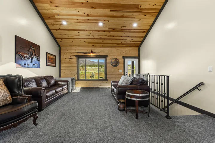 Spacious room featuring vaulted wood-plank ceilings with recessed lighting, shiplap accent wall, and gray carpeting