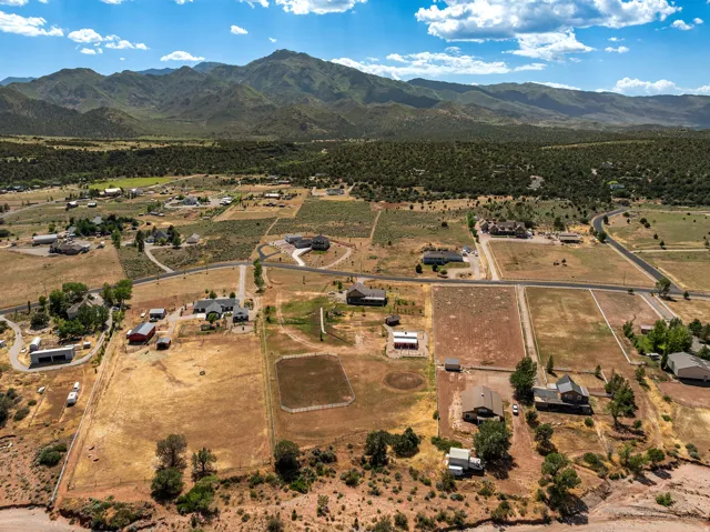 Expansive rural landscape featuring multiple parcels, scattered residential structures, open fields, and distant mountains