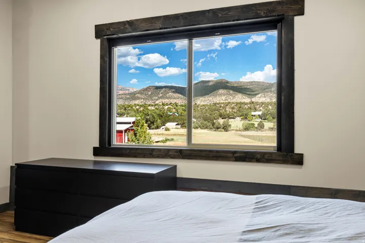 Expansive window with dark wood-finish trim, offering a panoramic mountain and valley backdrop